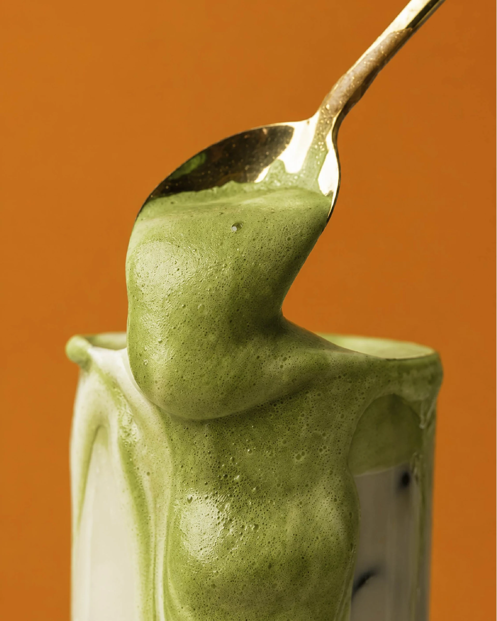 Krämig grön matcha chai med skum i ett glas.