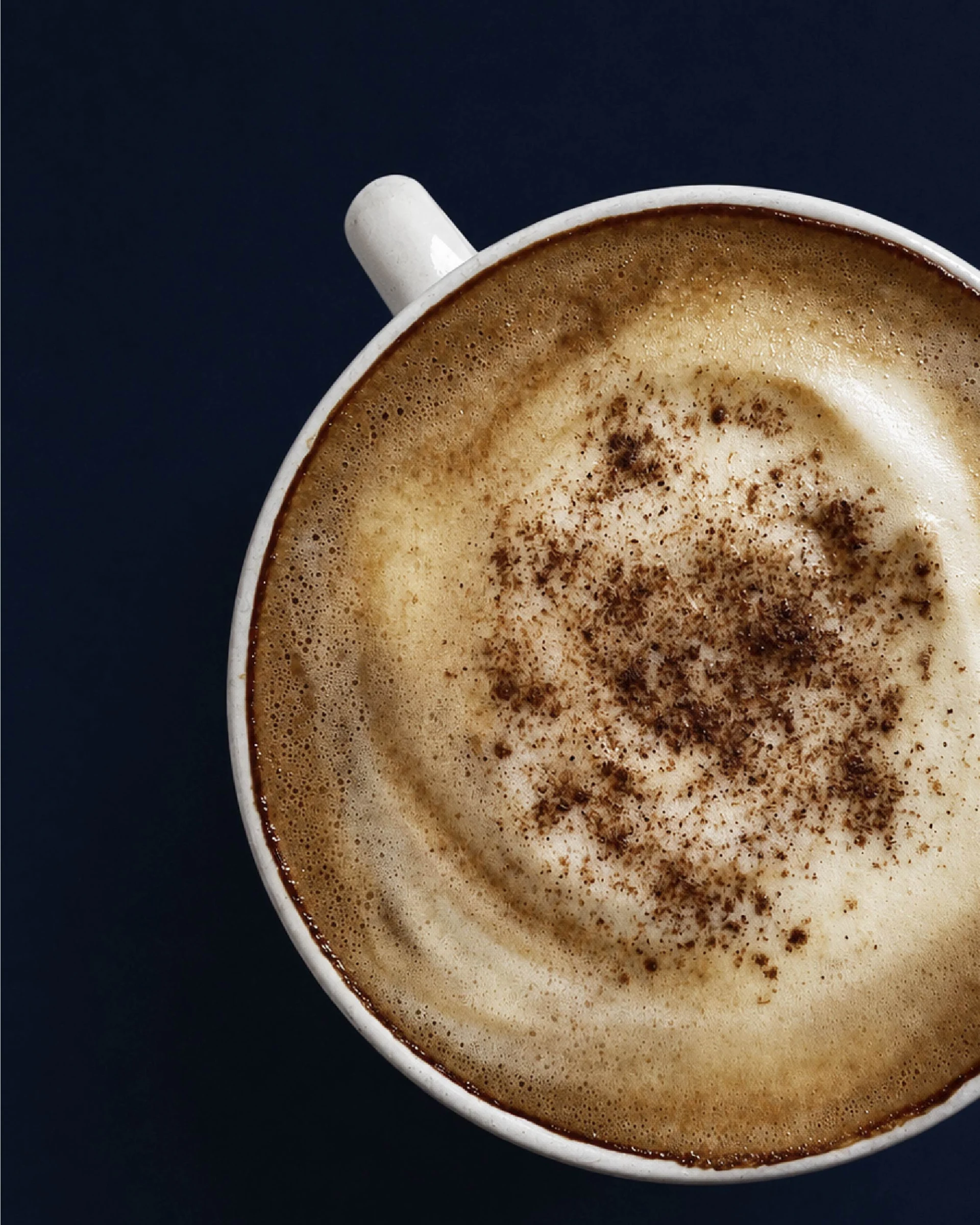 En kopp chai med ljust skum, fotograferad ovanifrån mot en mörk bakgrund.