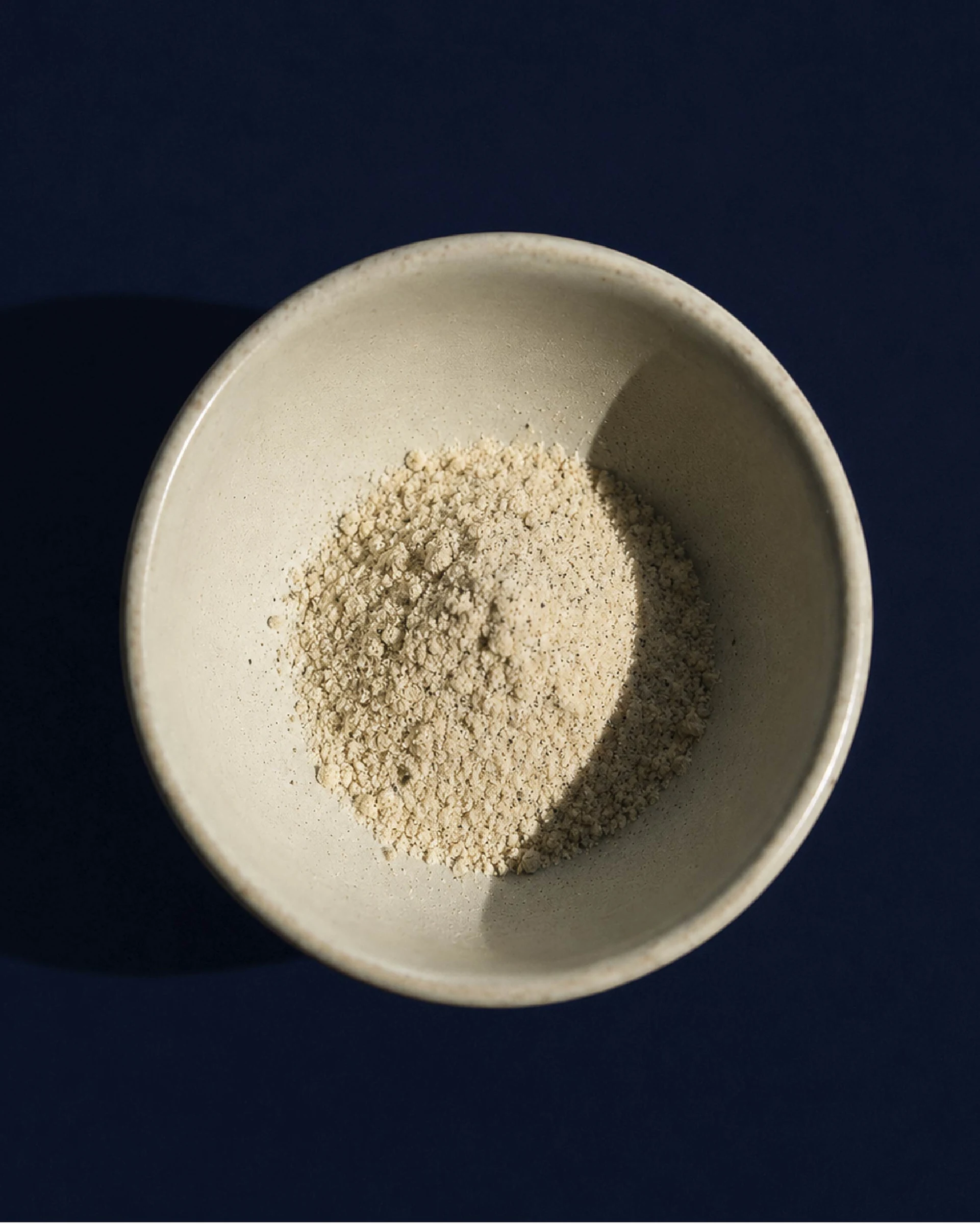 Ljust Vanilla Chai-pulver i en skål mot en mörkblå bakgrund.